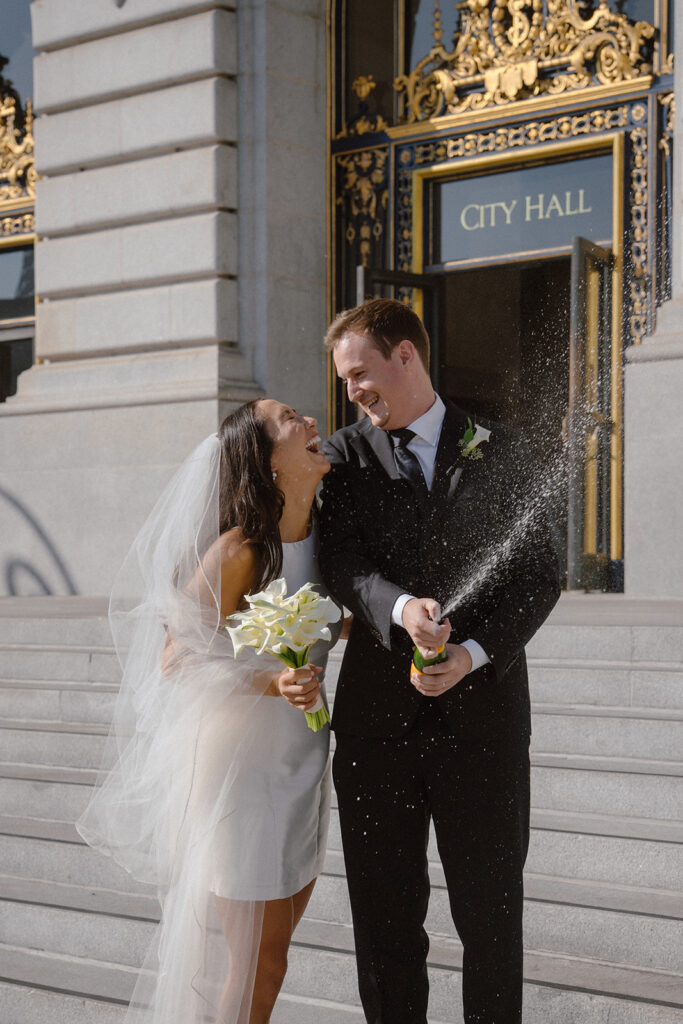 SF City Hall Civil Ceremony | Heech Studio & Co Couple pops bottle of champagne after their SF City Hall Civil ceremony appointment.