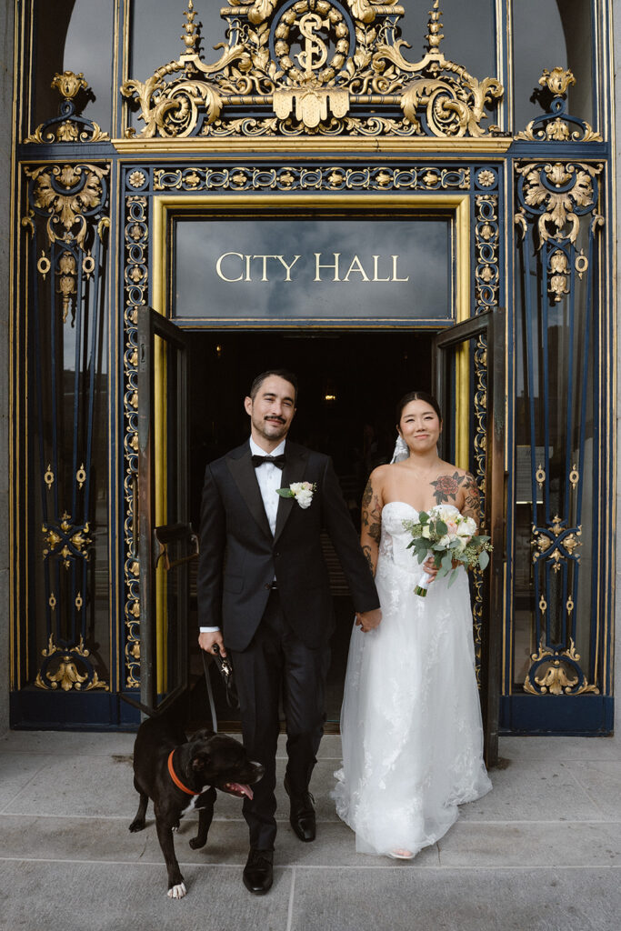 Couple walking out of City Hall together with their dog, after their San Francisco City Hall wedding ceremony/ 