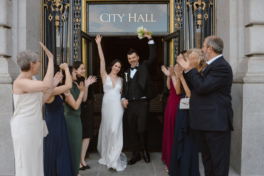 Couple celebrating with guests outside City Hall after their san Francisco City hall wedding ceremony reservation. 