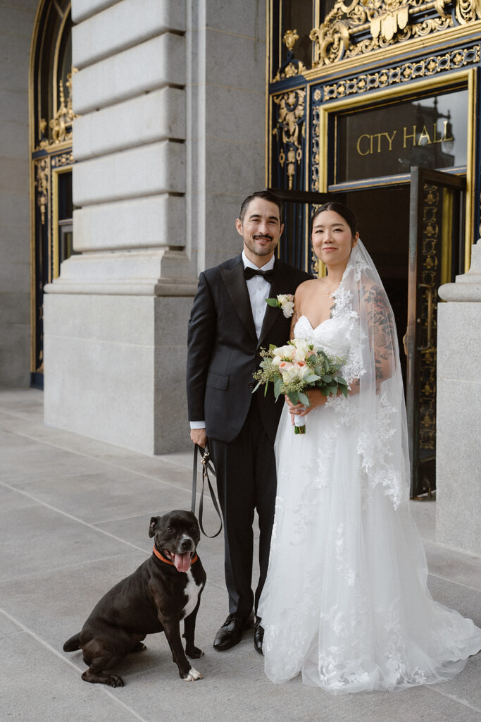 Couple posing with their dog outside City Hall after their SF City Hall Wedding Ceremony. 
