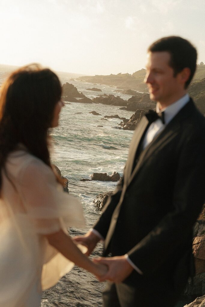 Couple holding hands with ocean view during Big Sur elopement.