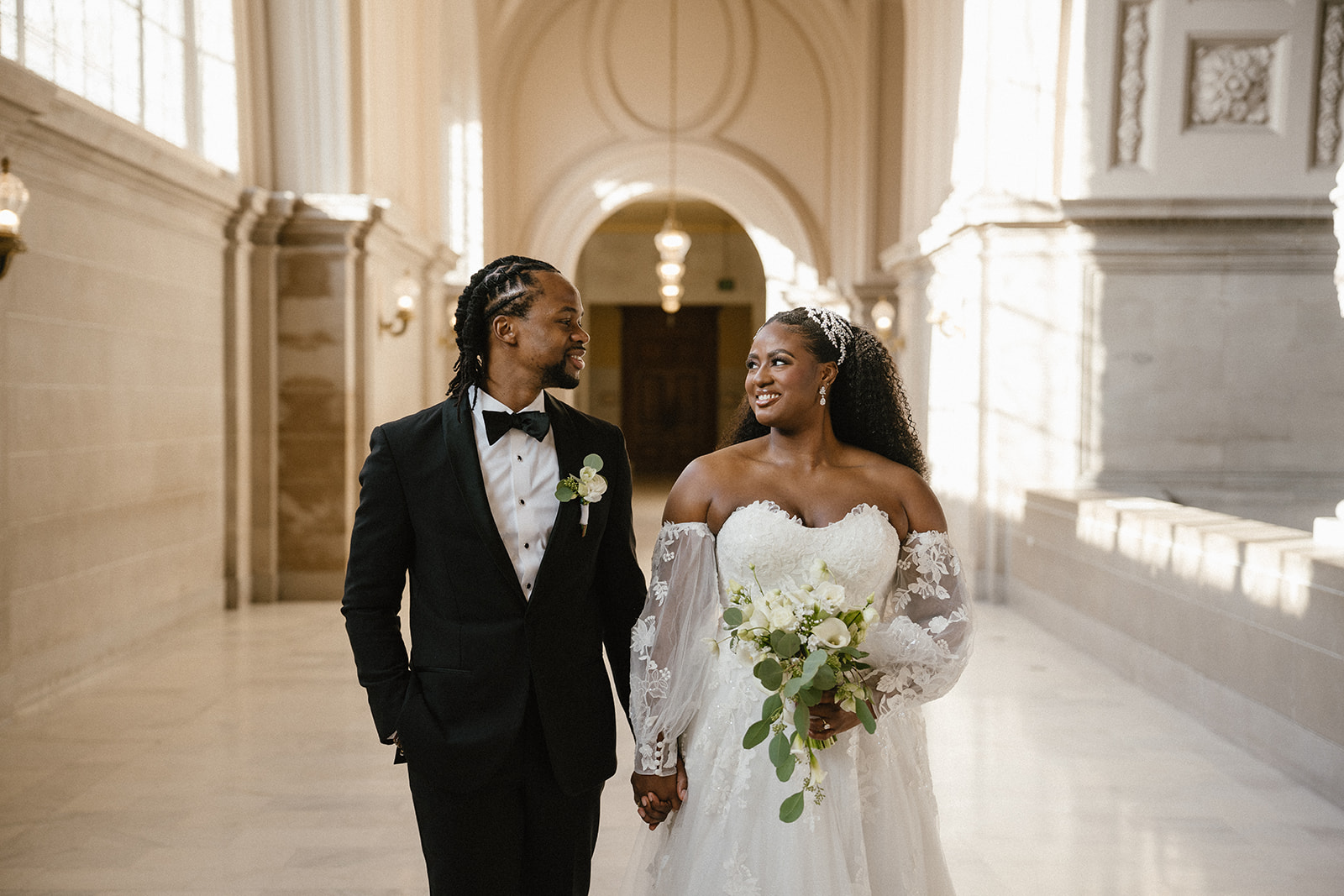 Mayor's Balcony San Francisco couple walking through the historic corridor at San Francisco City Hall with natural window light and bouquet details.