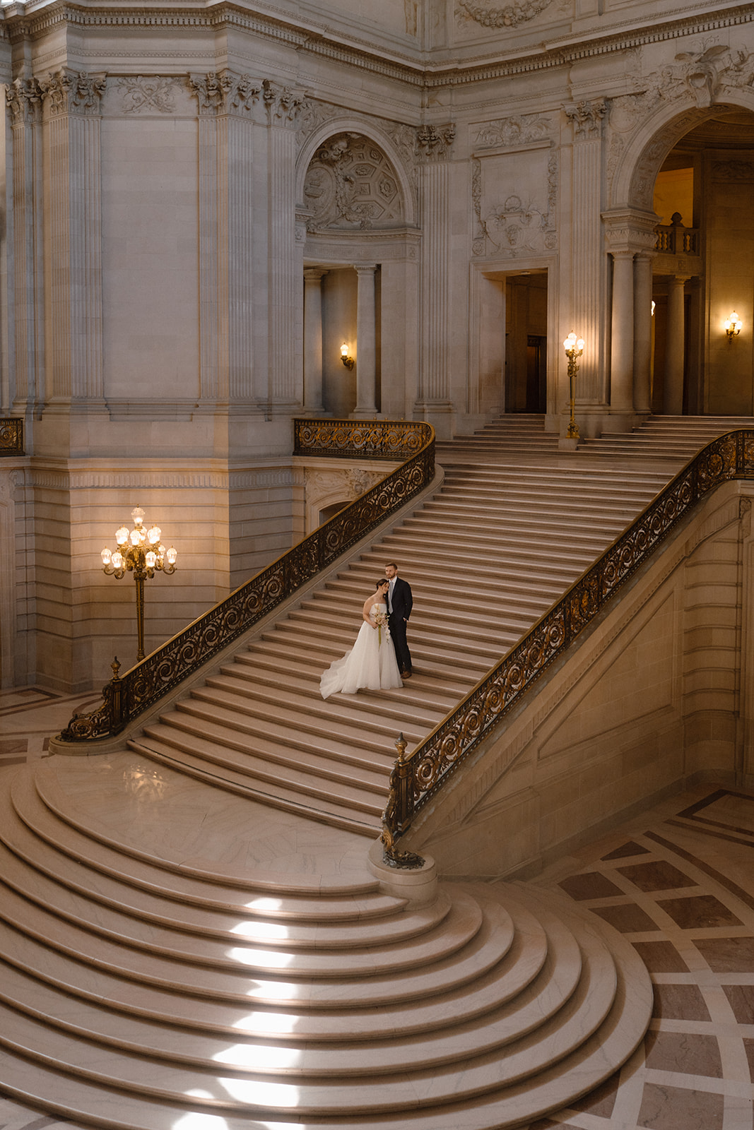 Bride and groom posing on the Grand Staircase during a San Francisco City Hall elopement.