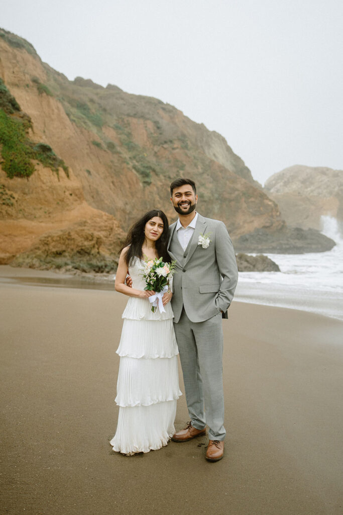Bride and groom smiling on the beach at Marin Headlands, Rodeo Beach