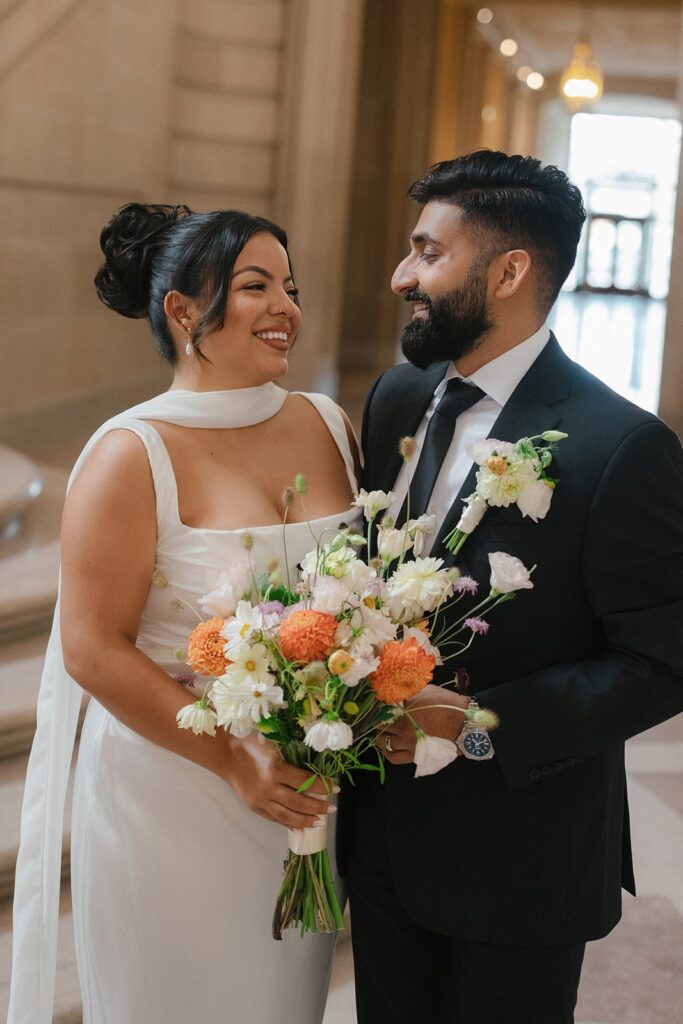 A bride and groom smile at each other after saying I Do
