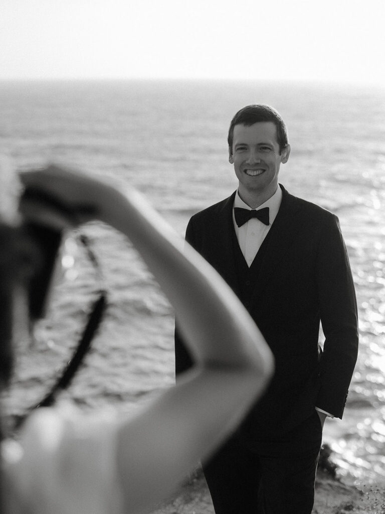 Cliffside intimate wedding at Big Sur with a bride taking a portrait of the groom