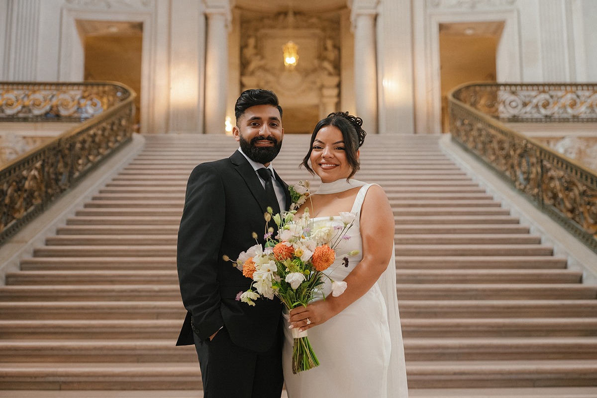Wedding couple holding a bouquet on the marble staircase at San Francisco City Hall